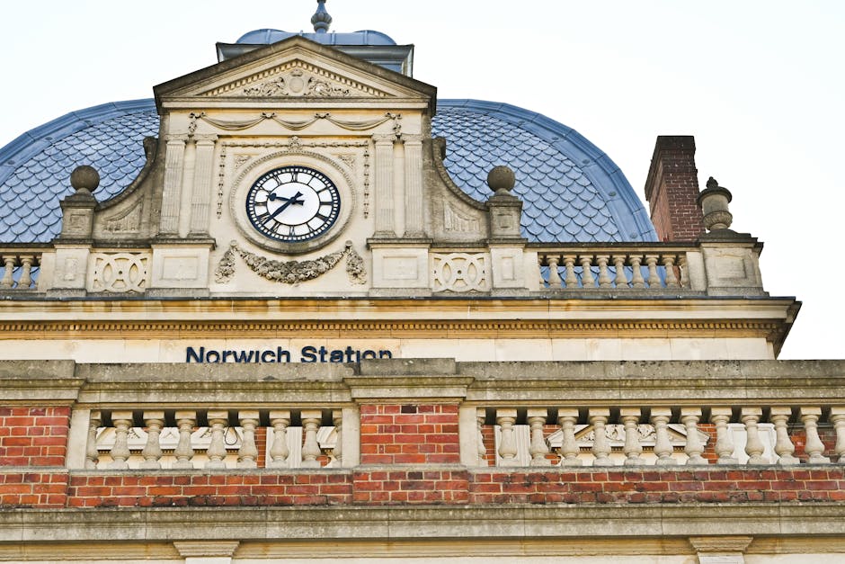 A white man with a black shirt is in the process of loading or unloading furniture and cardboard boxes from a moving truck parked on a street in Dulwich. The truck has an open side panel, revealing mo